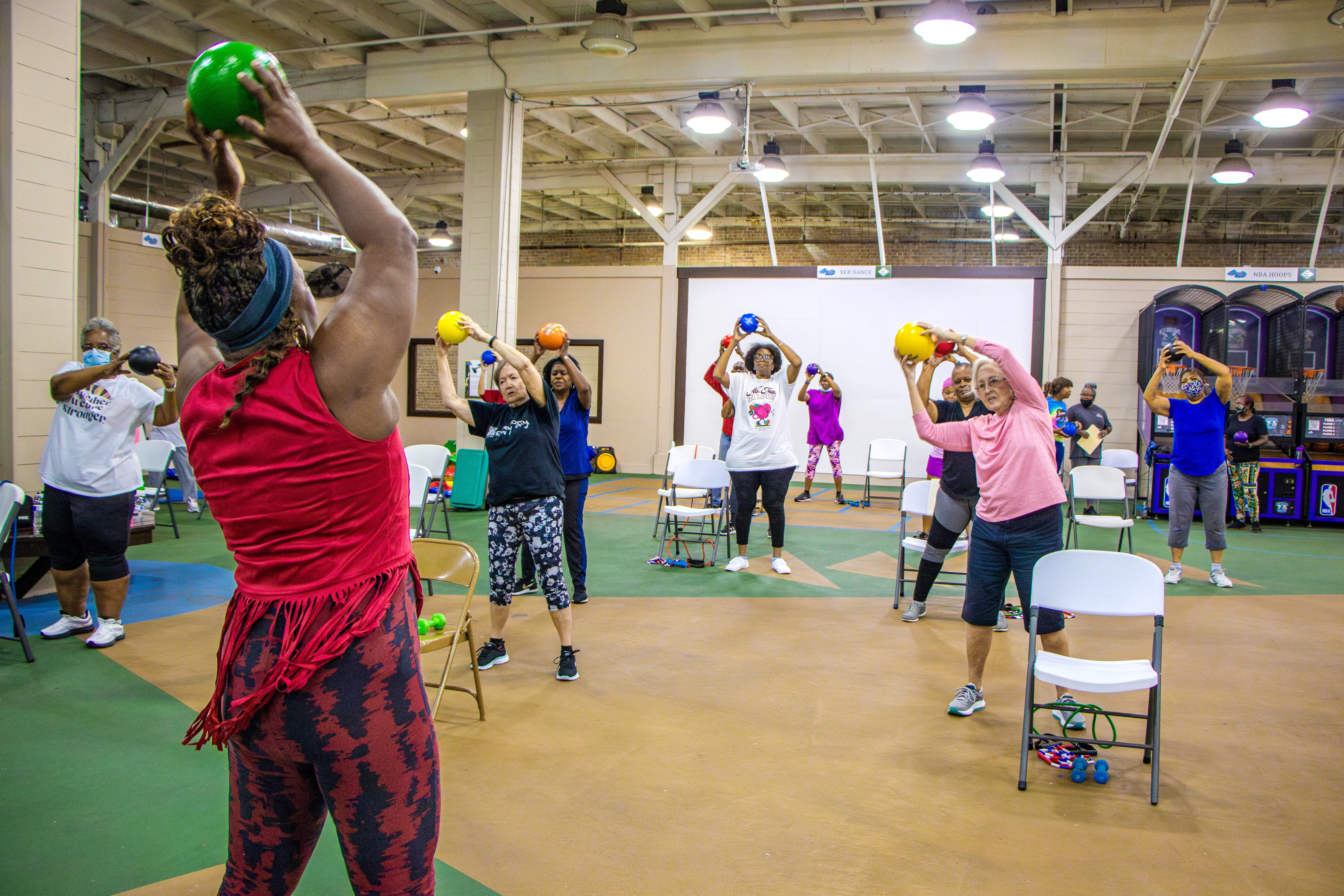 class of adults holding up workout balls during workout class