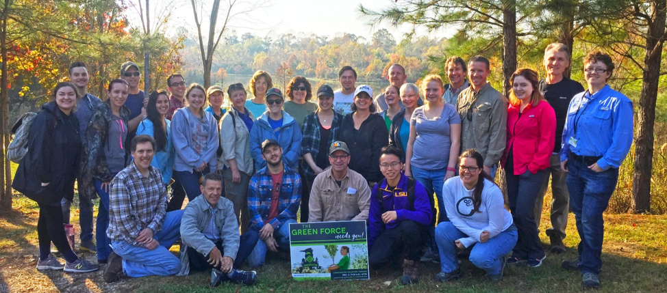 Photo of group of people posing with green force sign