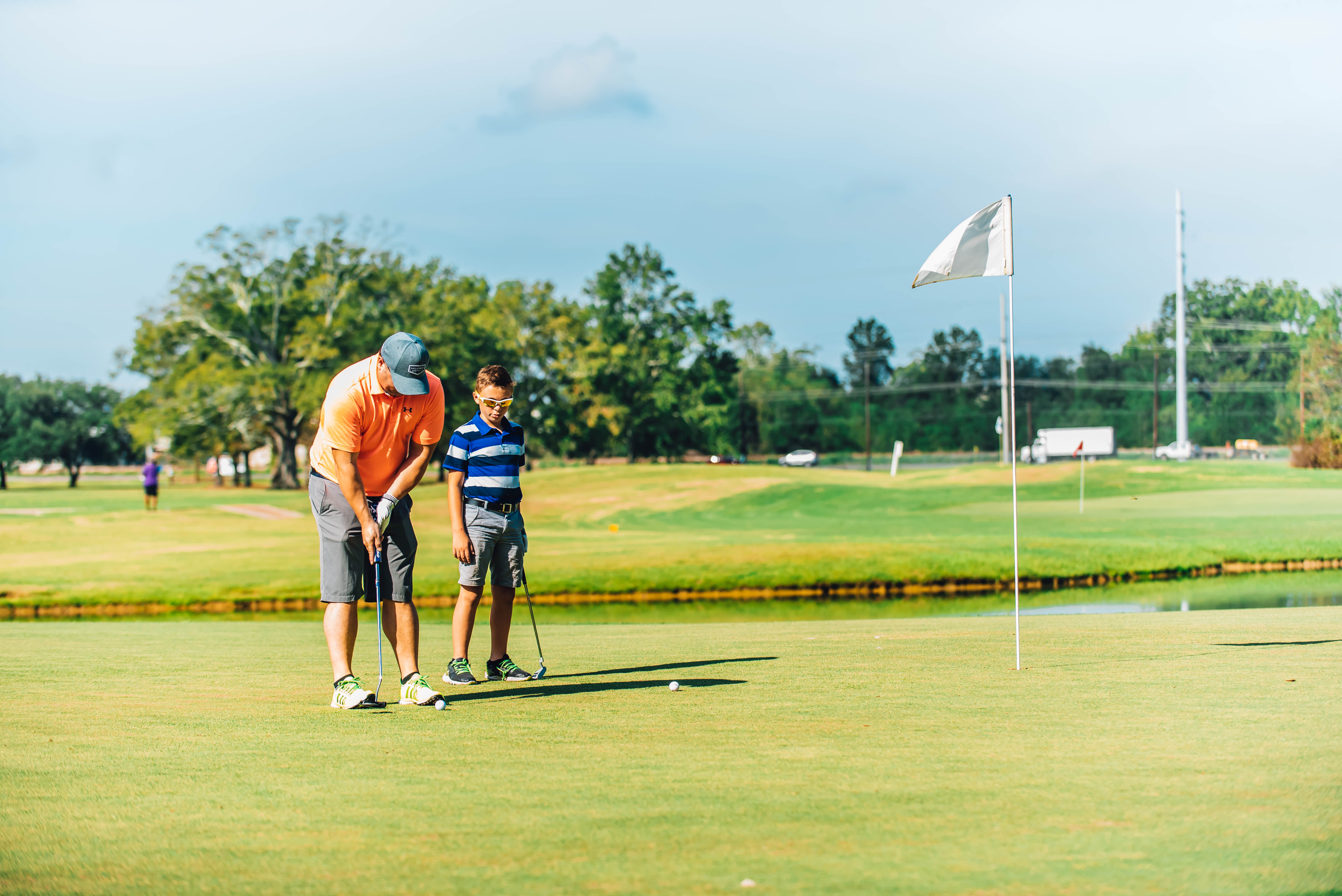 older golfer teaching young kid to golf