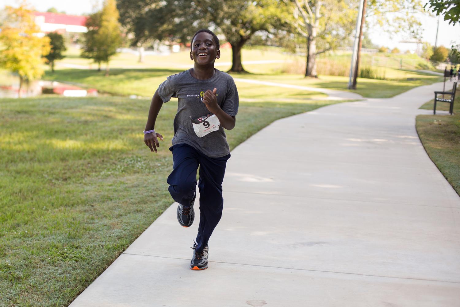 Boy running along cement trail in park