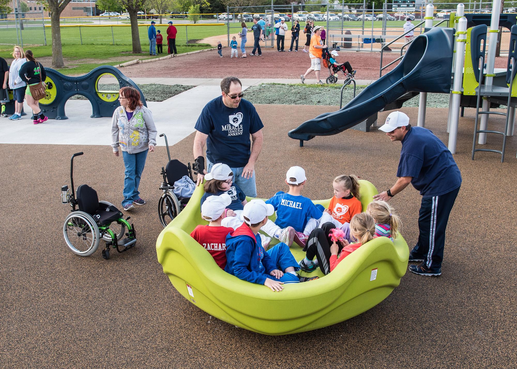Children with mobility challenges play on adaptive merry-go-round.